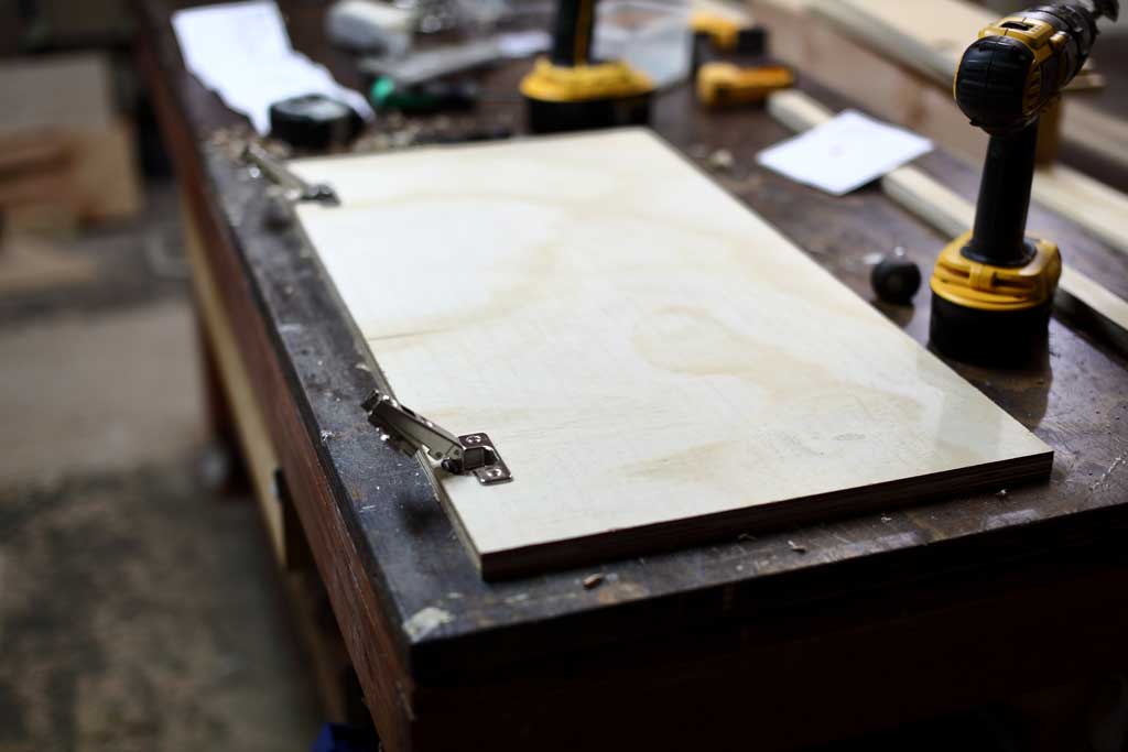 attaching the hinges to the door of the DIY Garage Cabinets