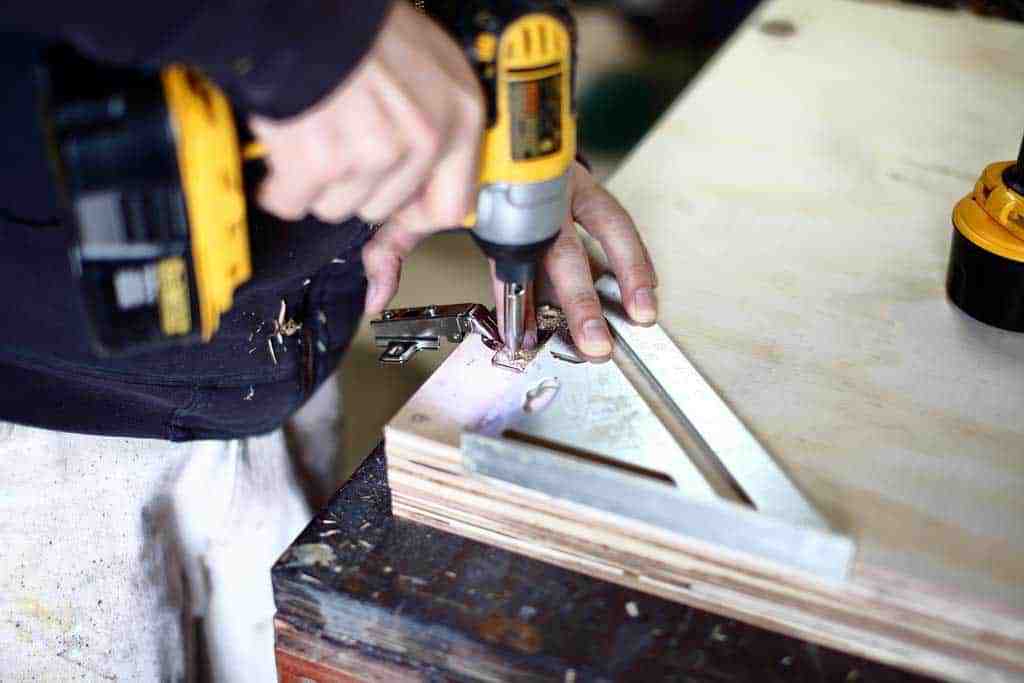 pre-drilling the holes for the hinge of the DIY Garage Cabinets