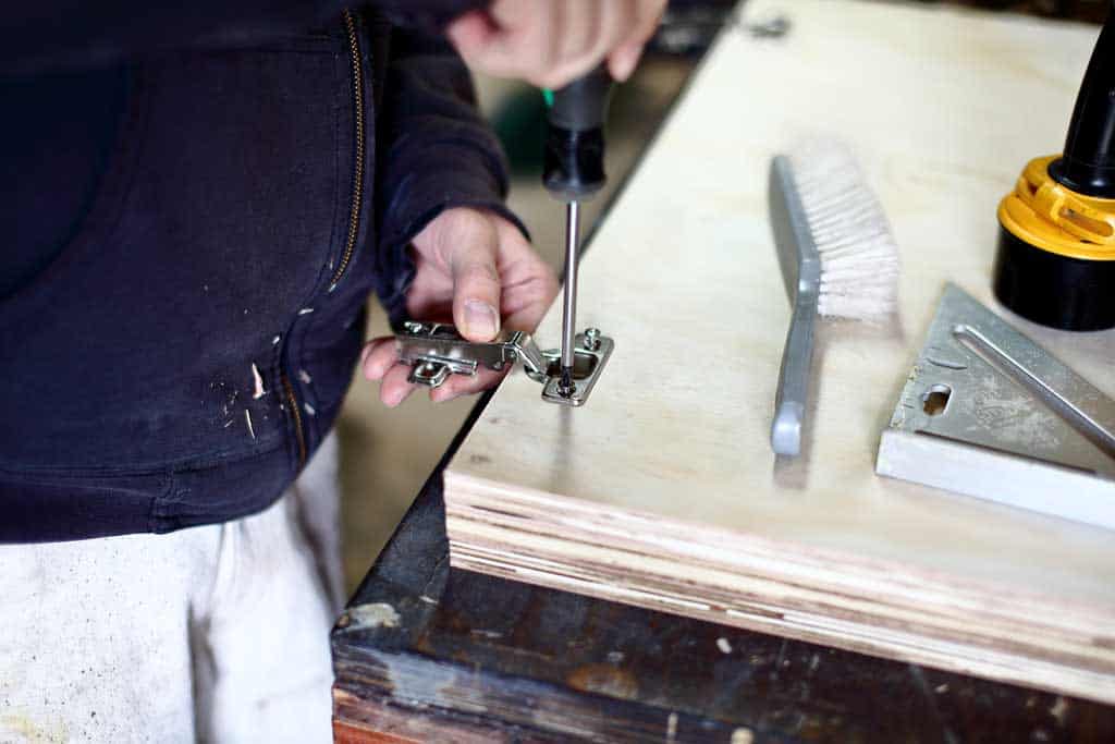 screwing in the door hinge for the DIY Garage Cabinets