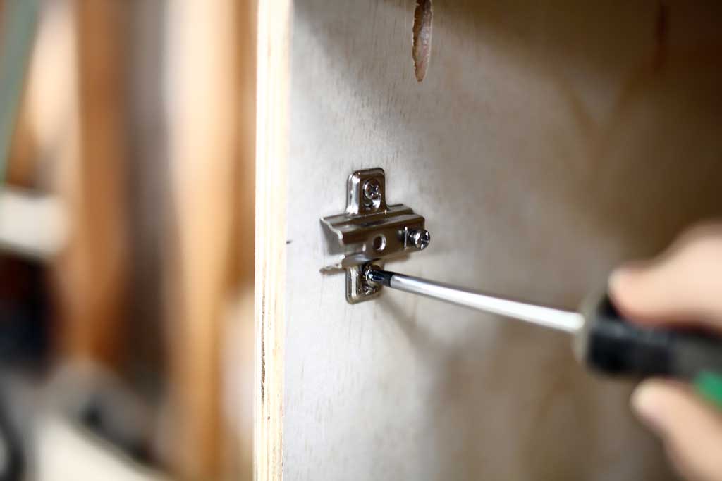 attaching the door hinge to the DIY Garage Cabinets