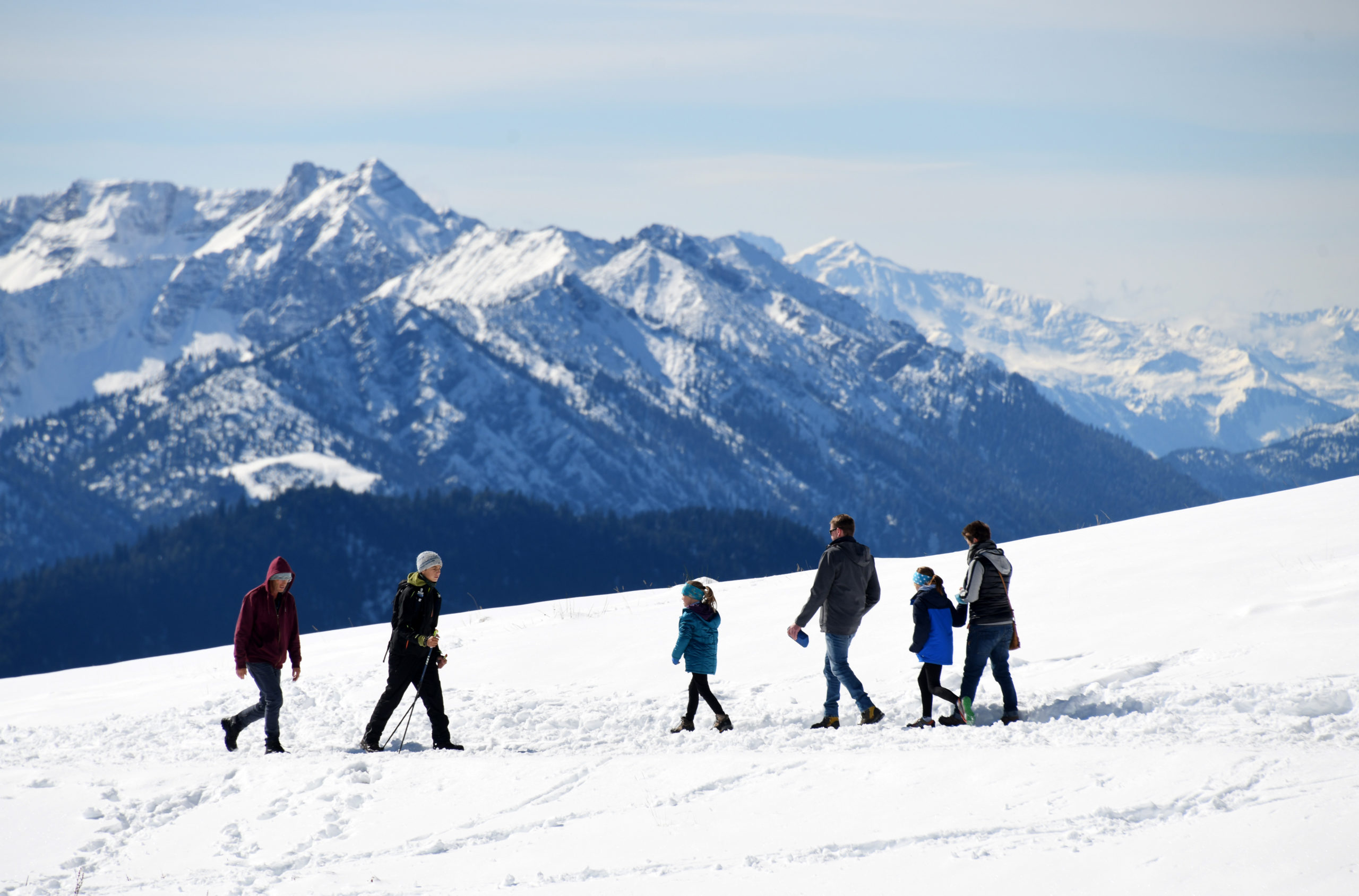 Hikers walk along a snow-covered hiking trail