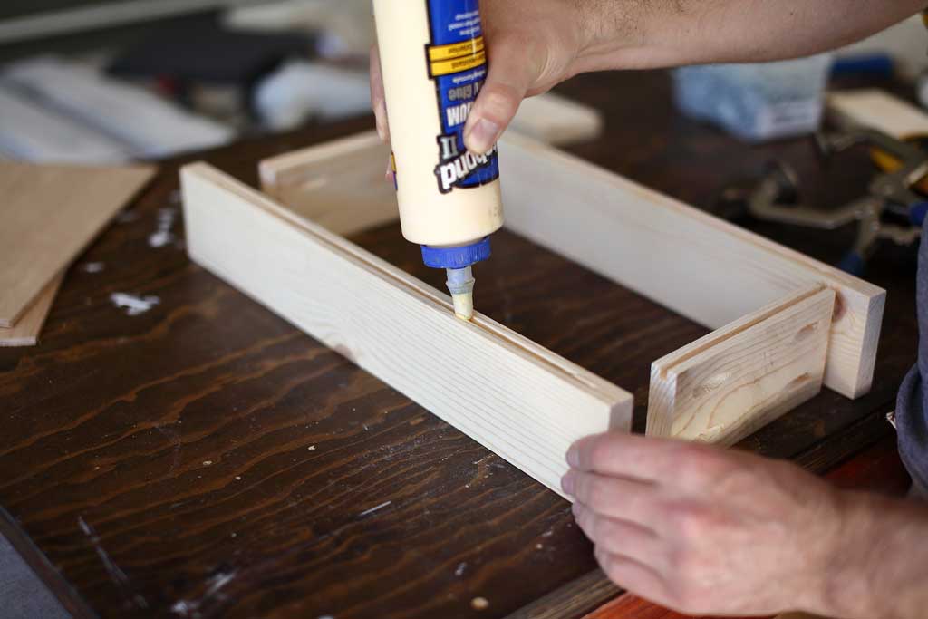 applying wood glue in groove for plywood panel