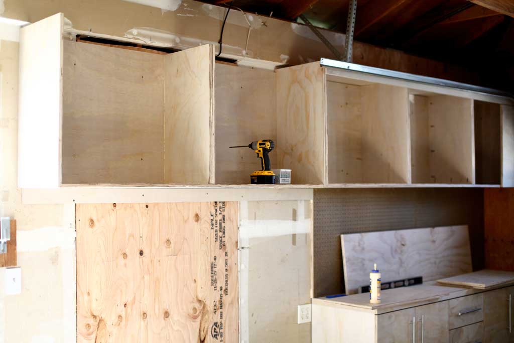 attaching the frame of the attaching the top piece of the garage cabinets to the wall