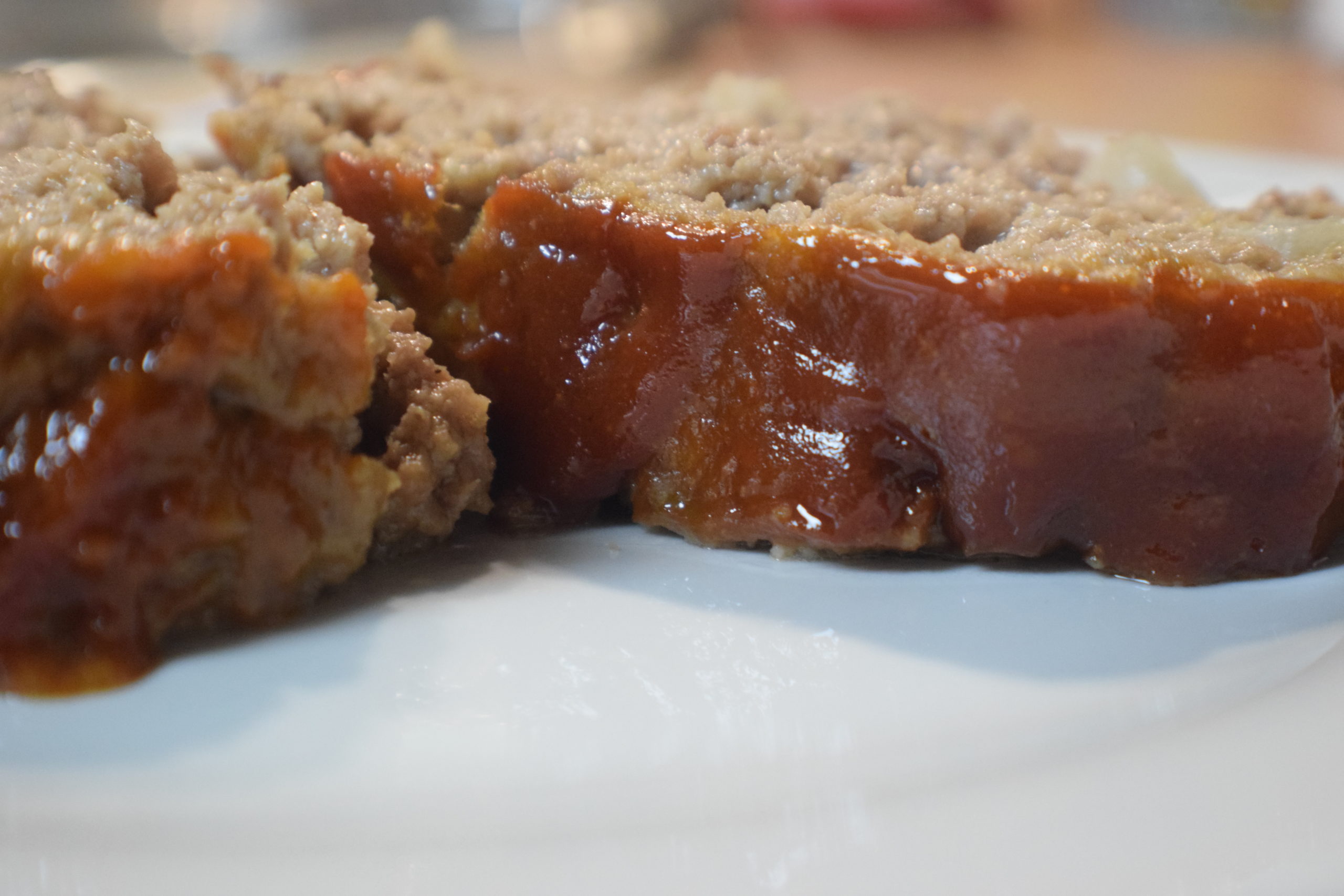 two pieces of meatloaf with red sauce on white plate