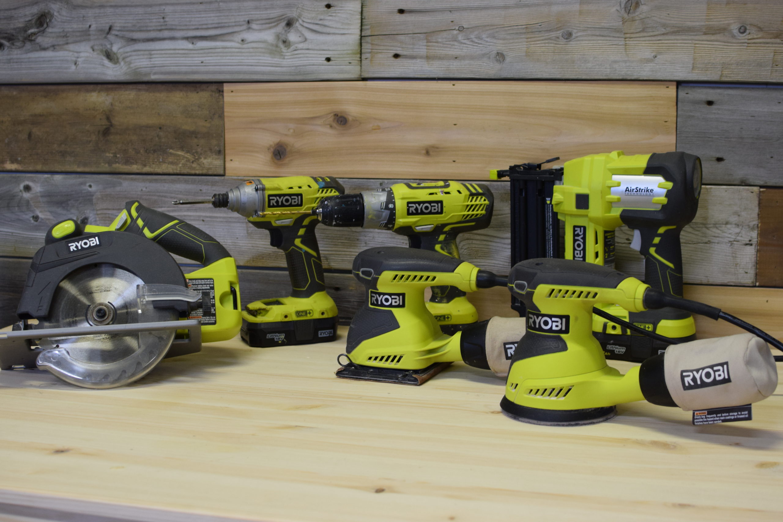 group shot of Ryobi tools on a wood table against rustic wood background