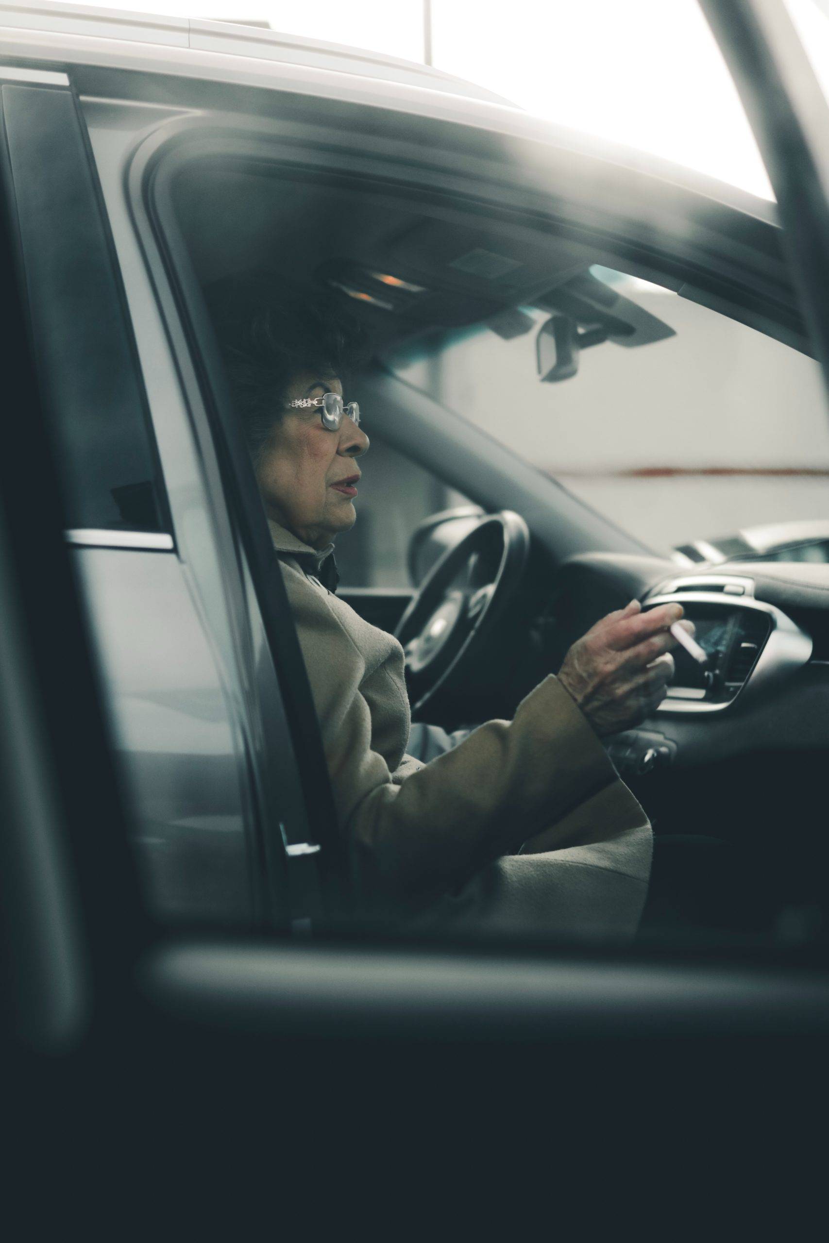 Old woman with cigarette sitting in a parked car