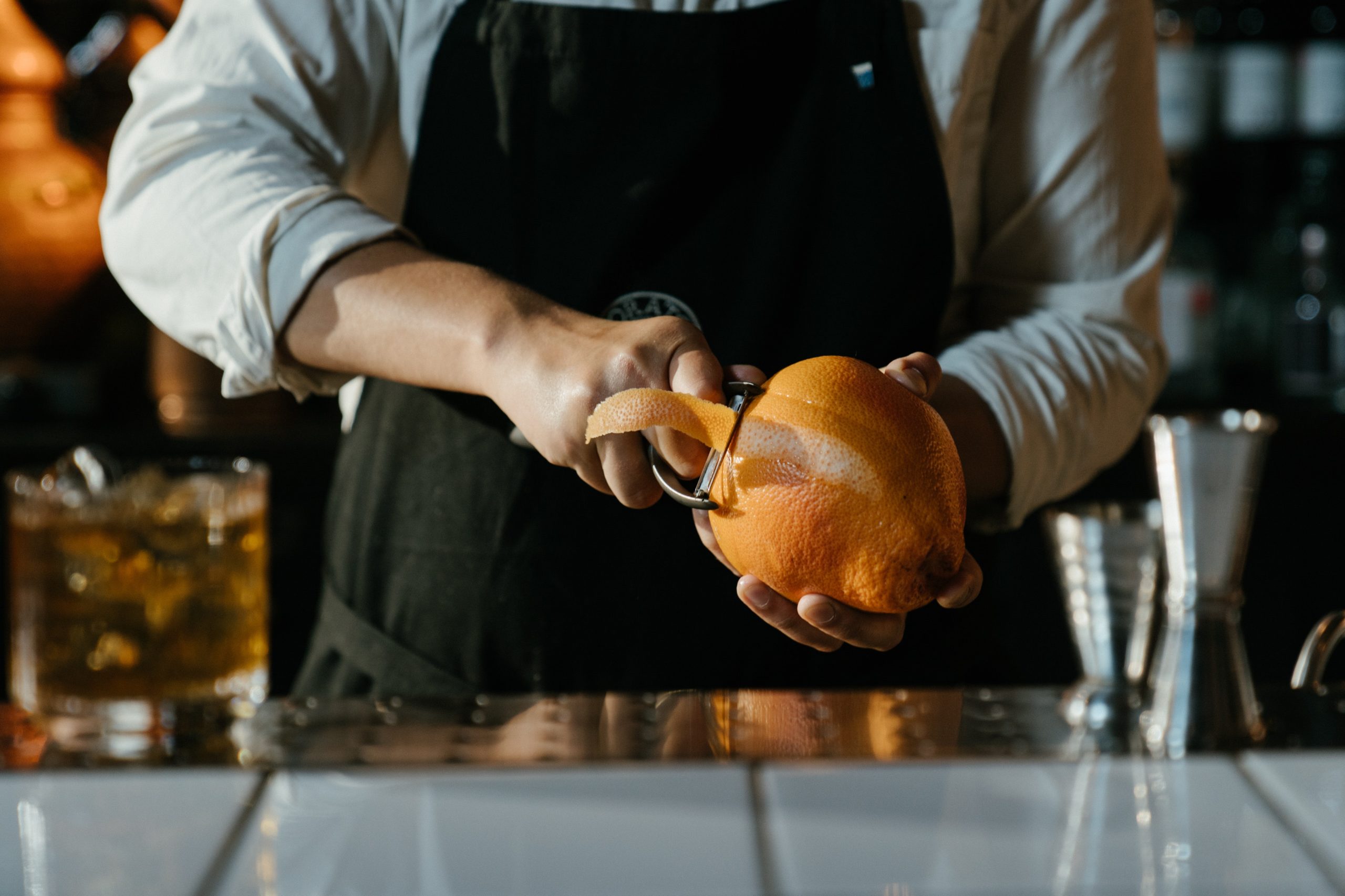 male bartender peeling orange zest in a bar