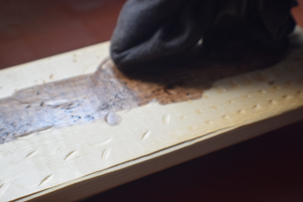 hand with black glove staining weathered wood