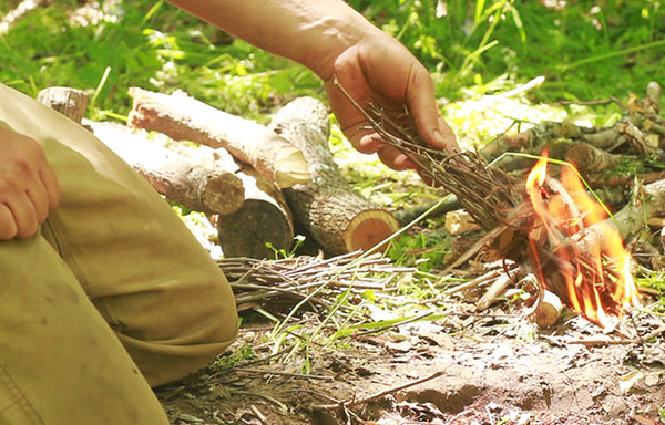 man starting fire with bundle of sticks