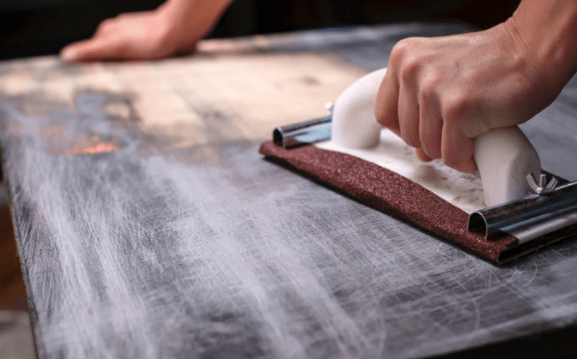 manual hand sander used on wood table