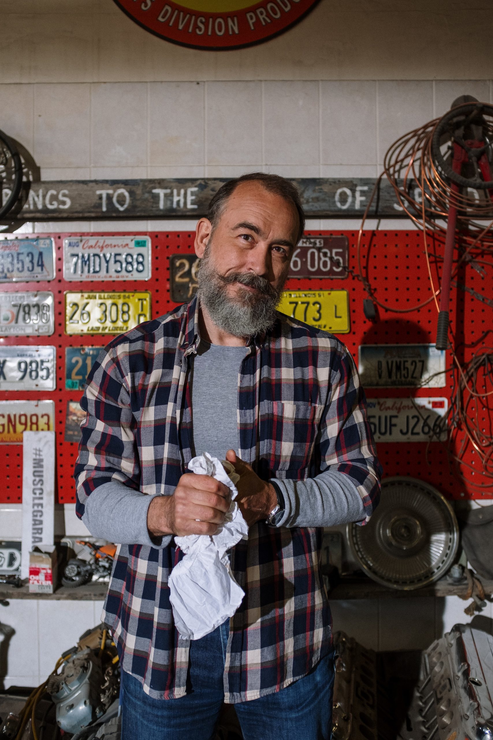 friendly male mechanic holding a rag and smirking with a mustache