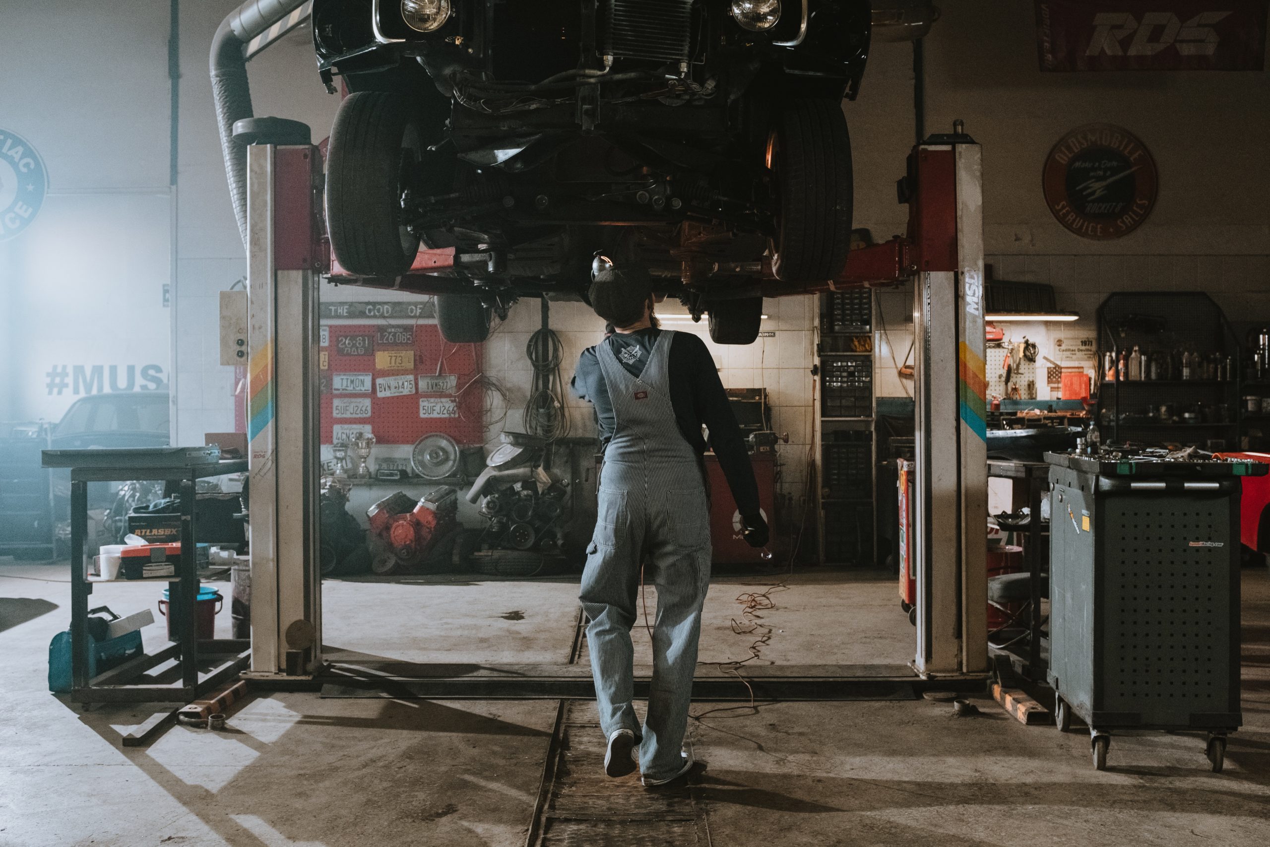 mechanic walking under a lifted car in the shop