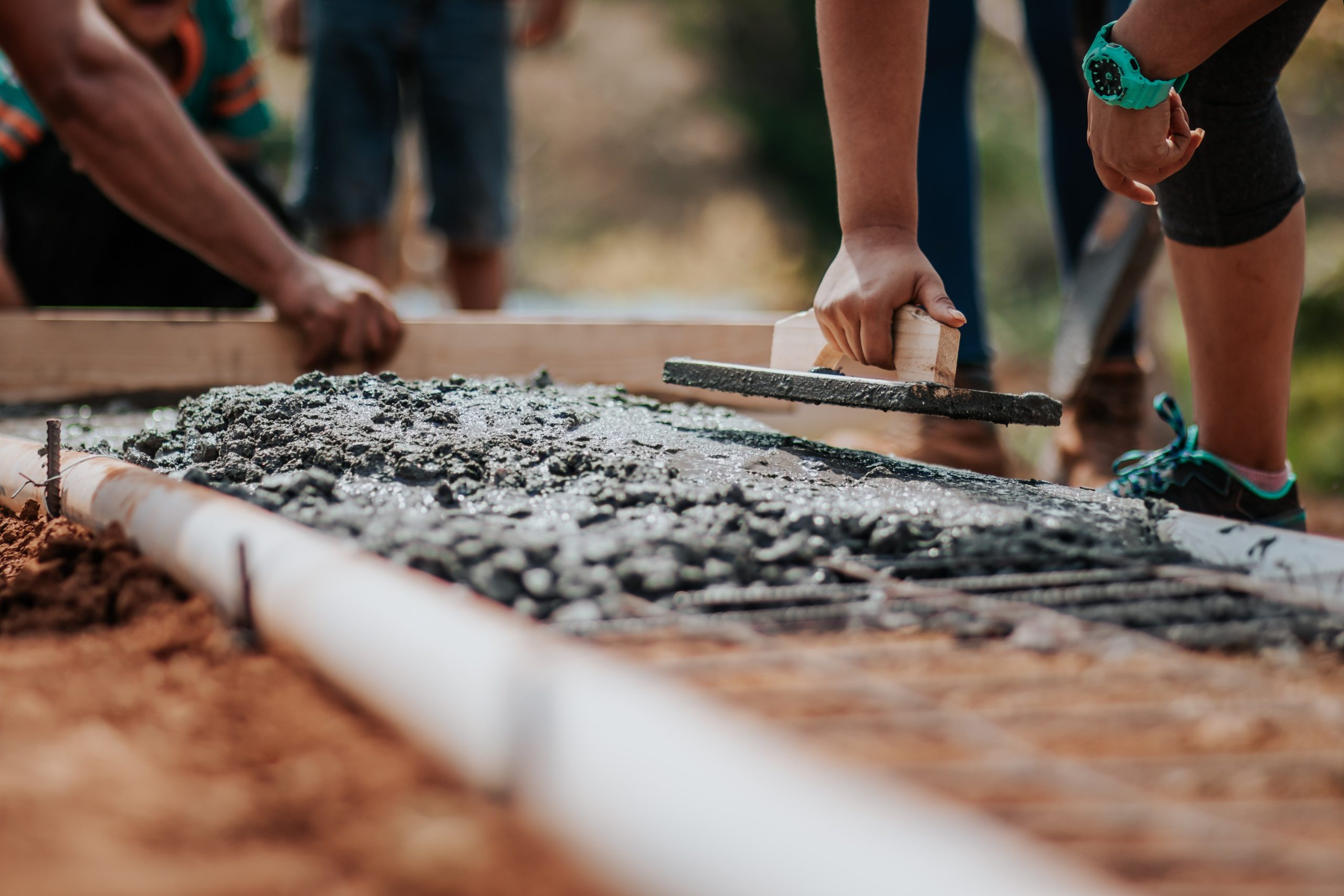 worker lays concrete mix down on ground