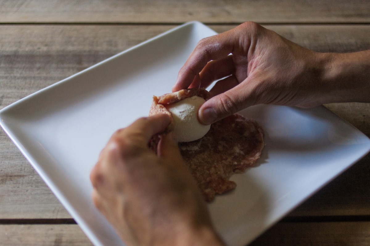 Rolling an egg in sausage