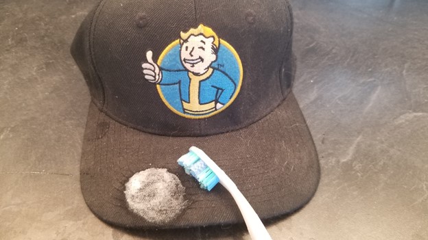 tooth brush spot cleaning a black baseball cap