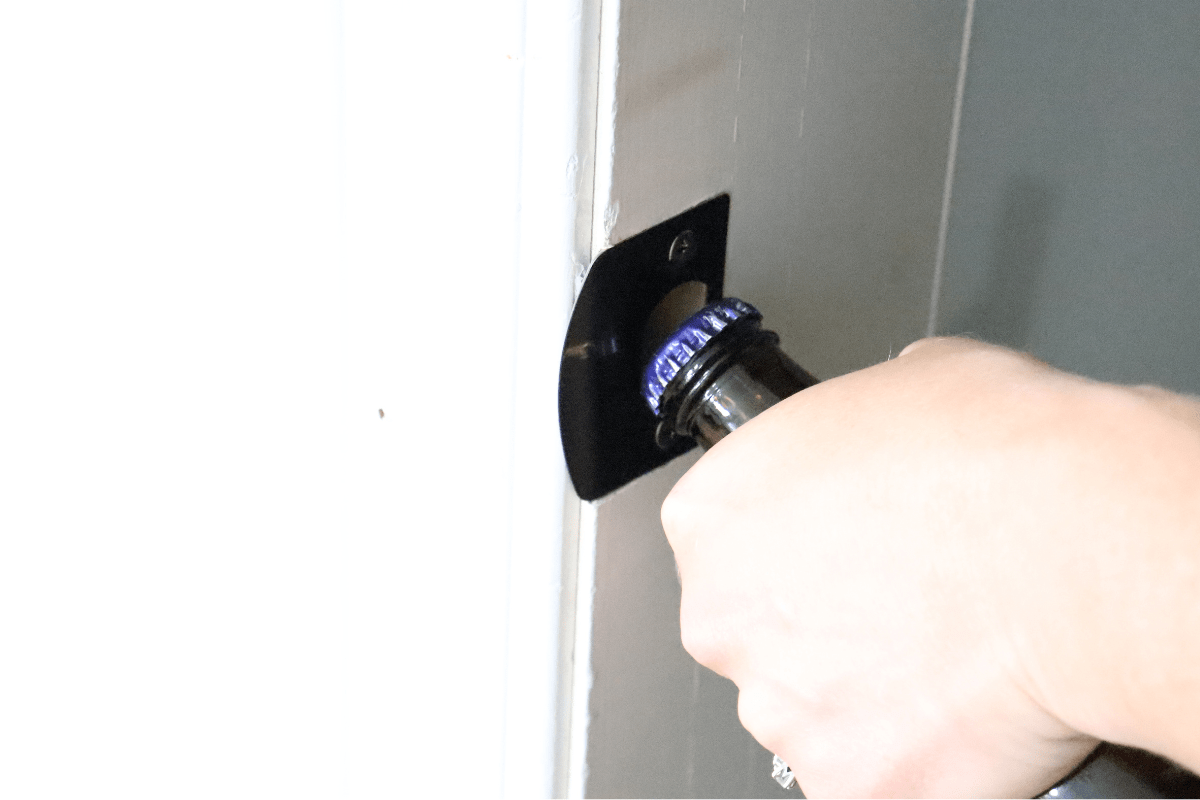 hand using door frame to open beer bottle white background