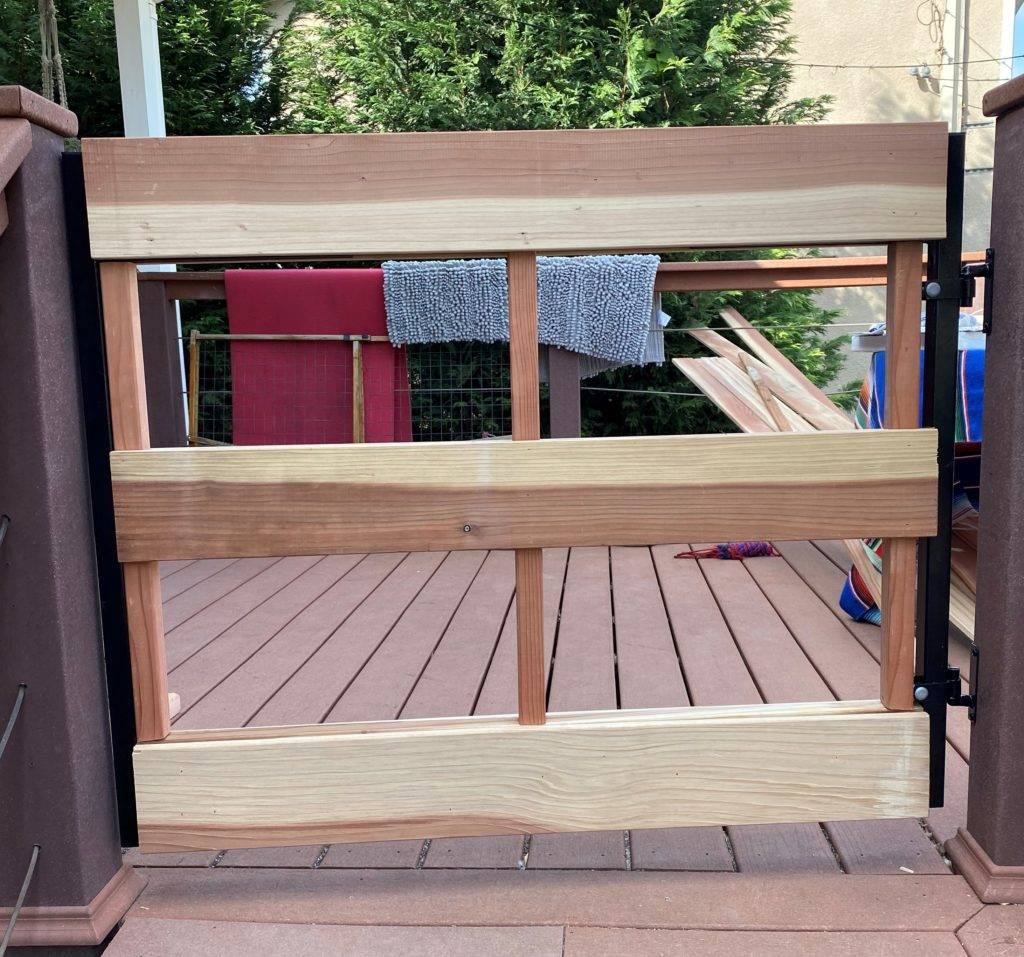 Vertical wood is attached to a metal deck gate frame