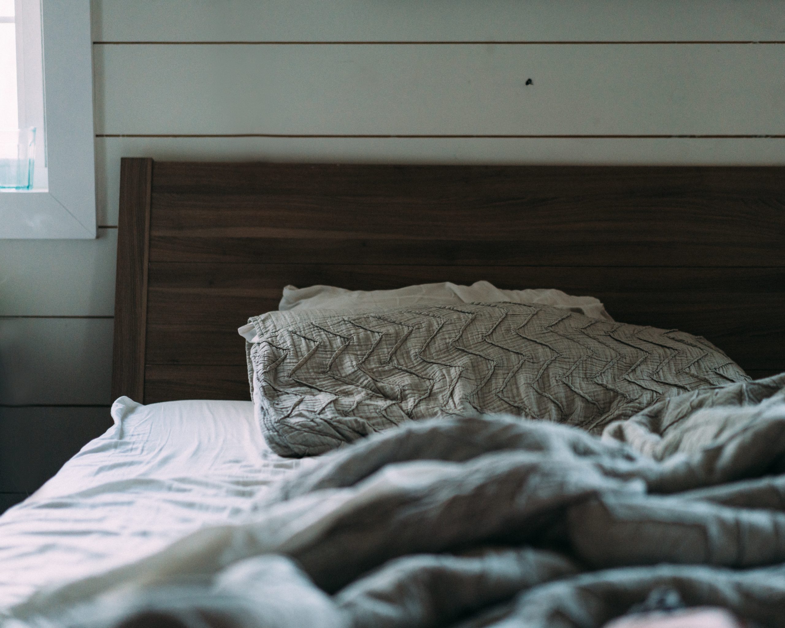 shiplap walls painted mint behind a bed headboard