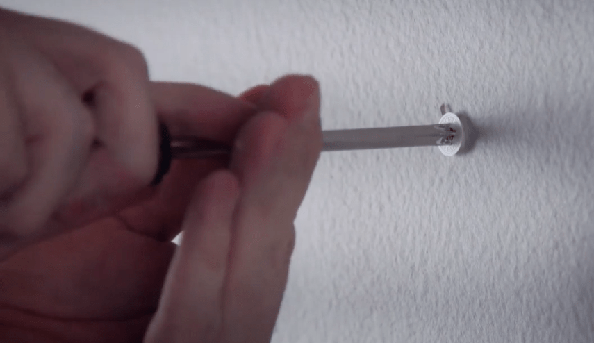 screwdriver being used to remove a drywall anchor