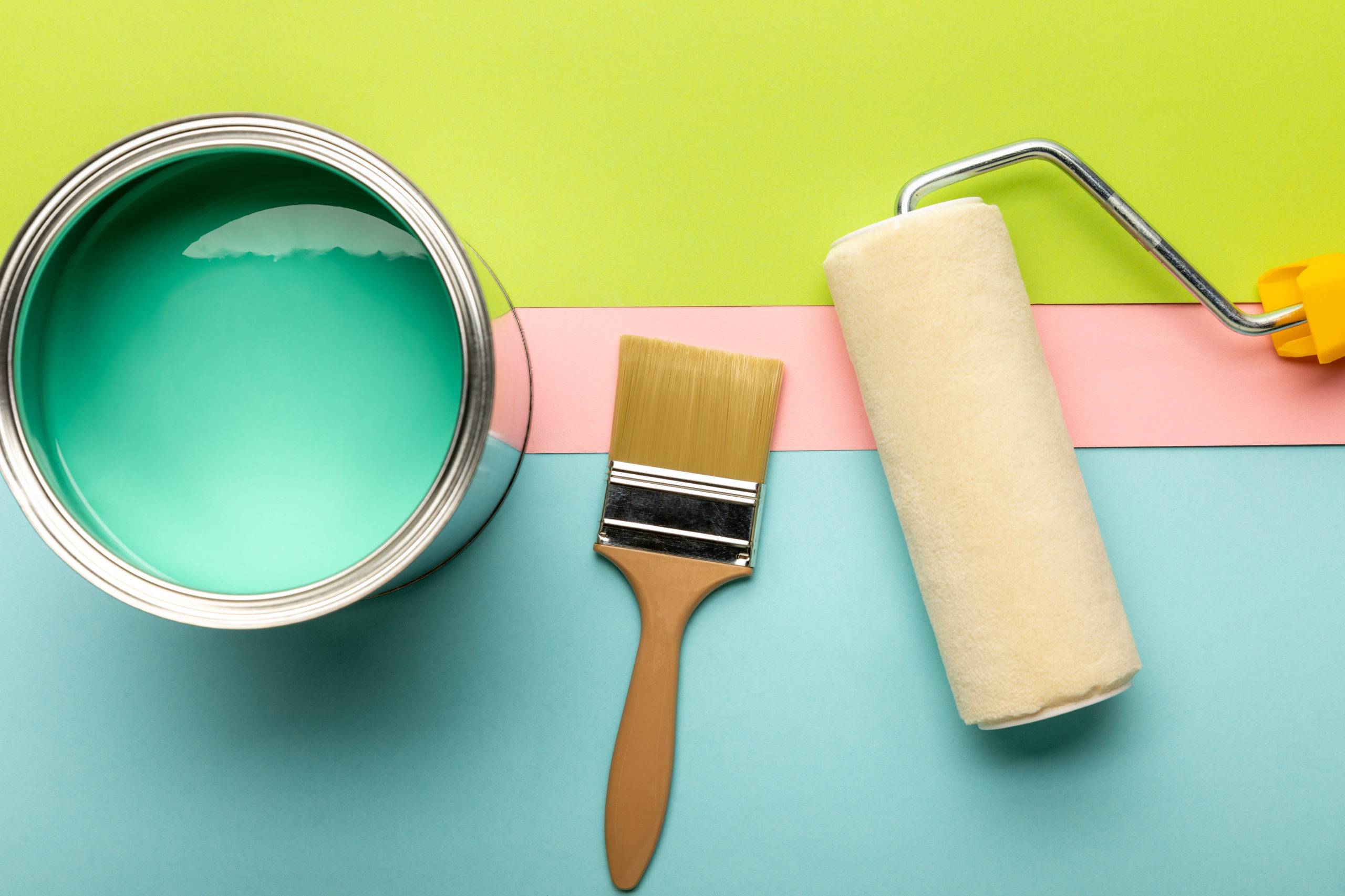 top view of tin with green paint, paint roller and brush