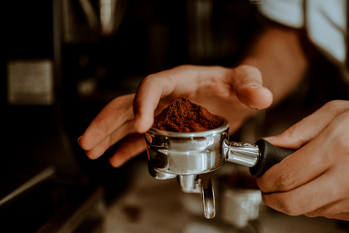 hand holding part of espresso maker, leveling out ground beans