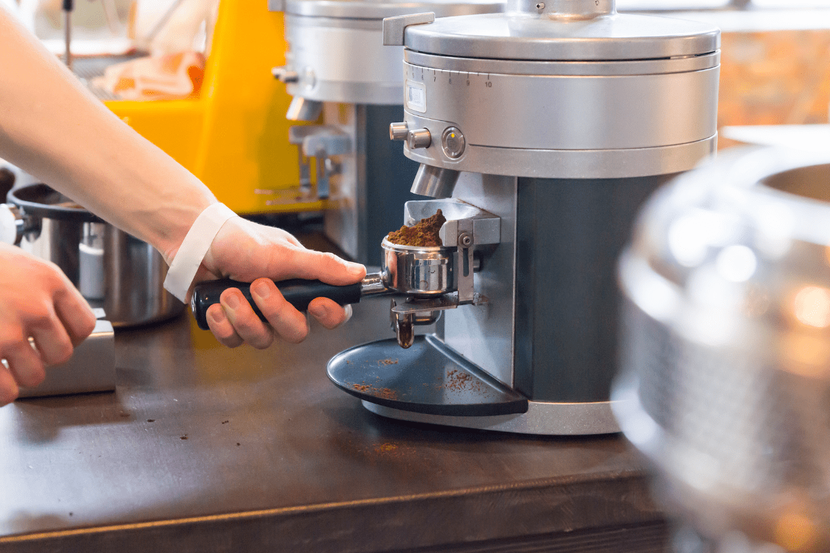 hand reaching towards silver espresso machine on counter