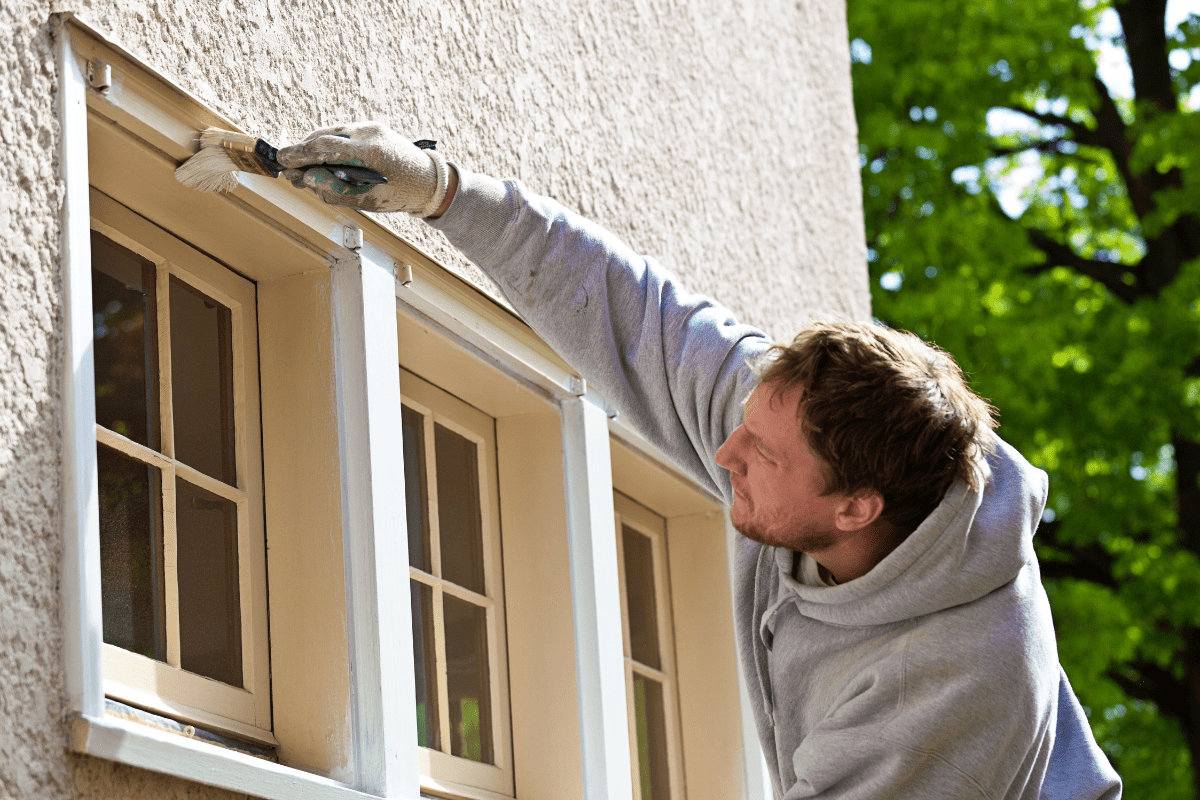 close up of man painting window exteriors