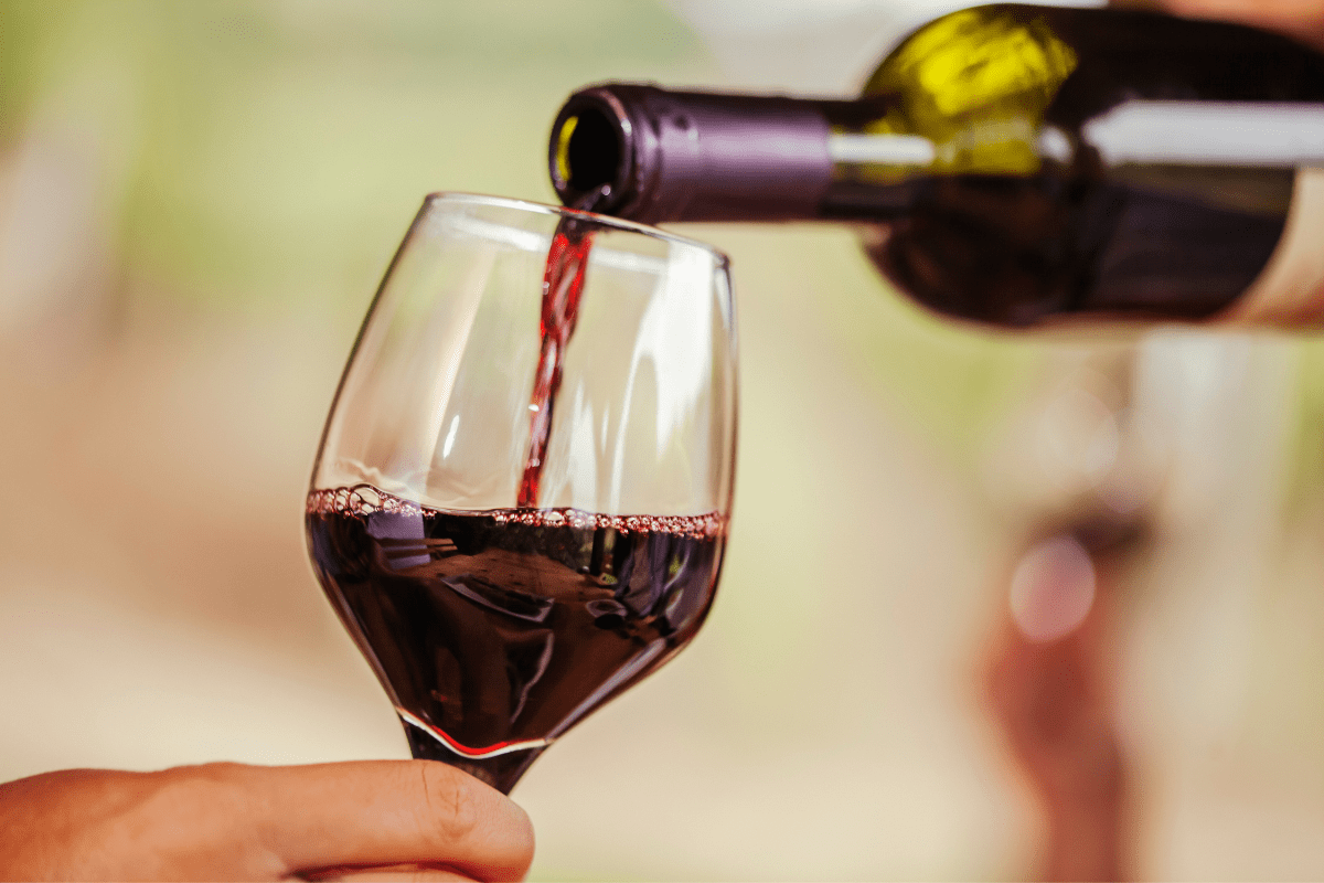 hand holding glass being filled with red wine