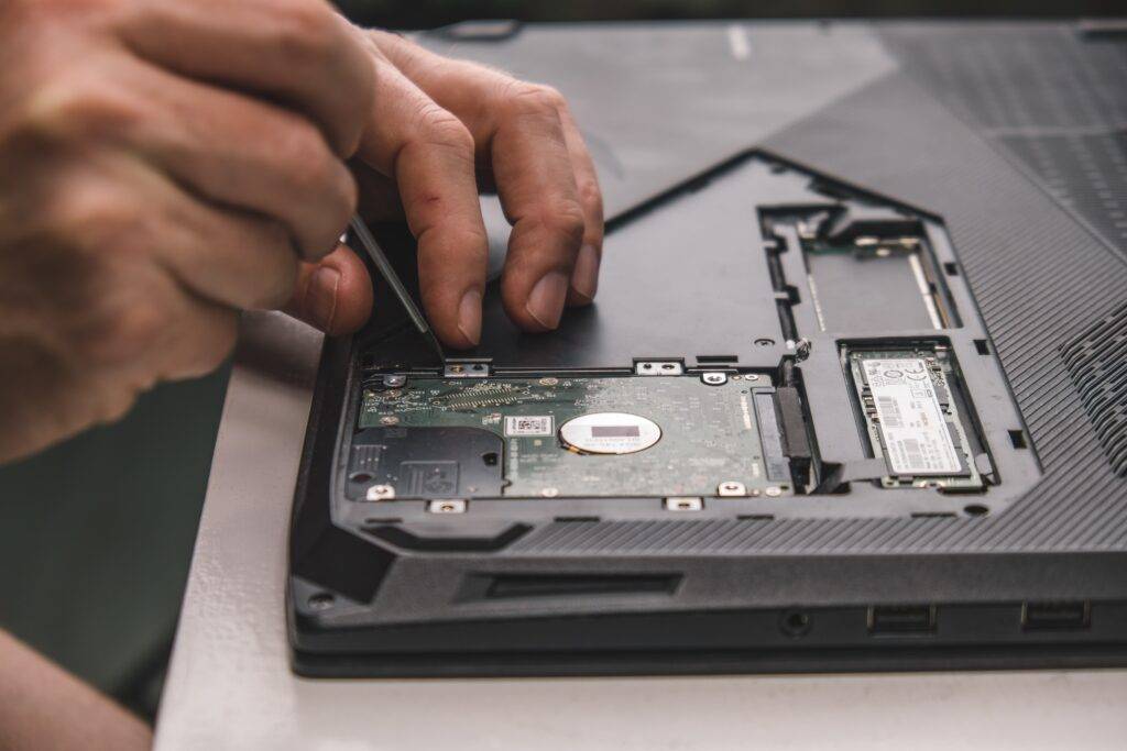 close up of man's hands using small tool to alter tech on laptop