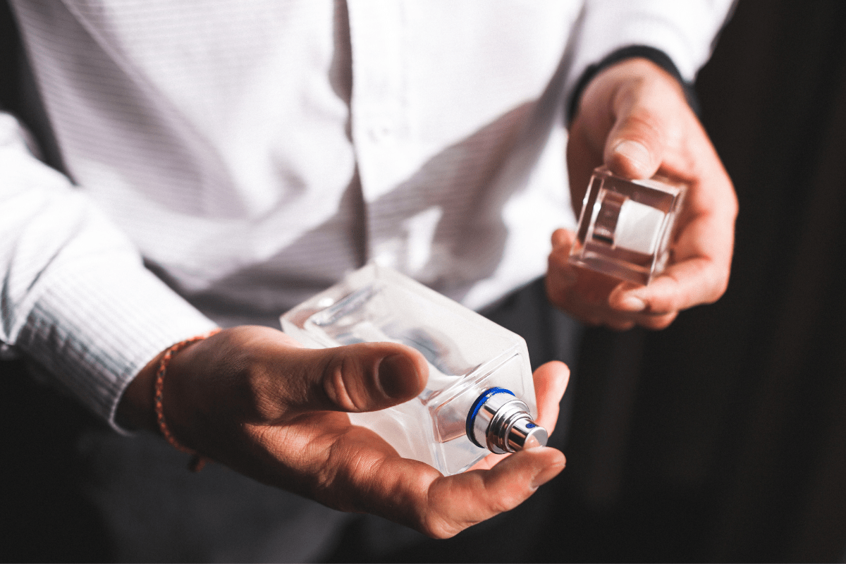 close up of man's hands holding a bottle of cologne