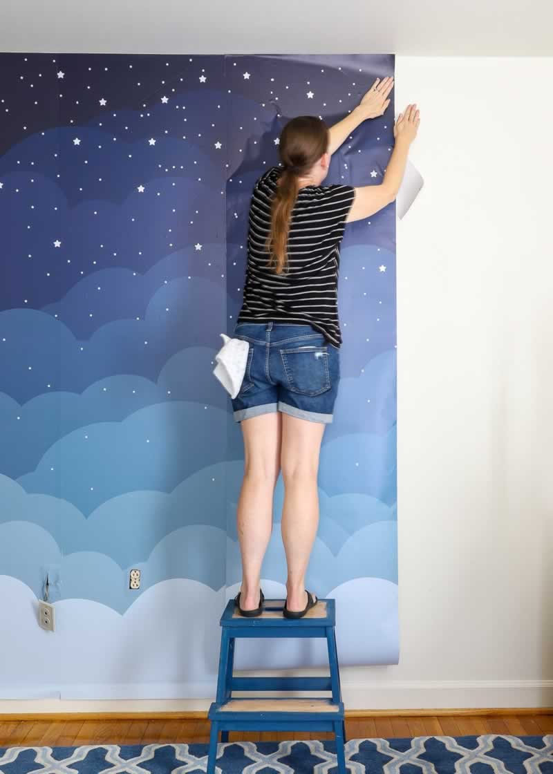 girl installing peel and stick wallpaper