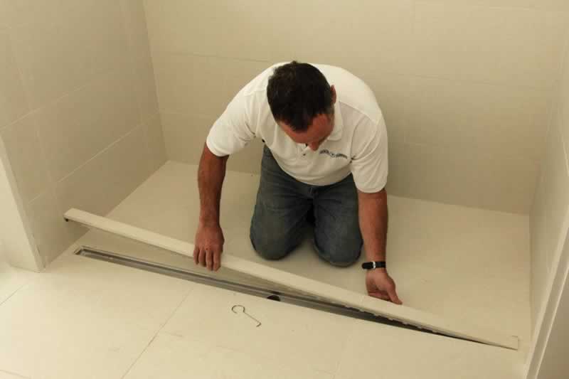 man installing linear shower drain