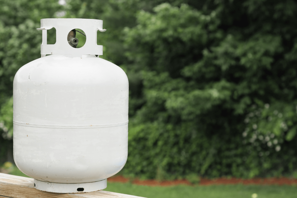 propane tank on deck railing with trees in background