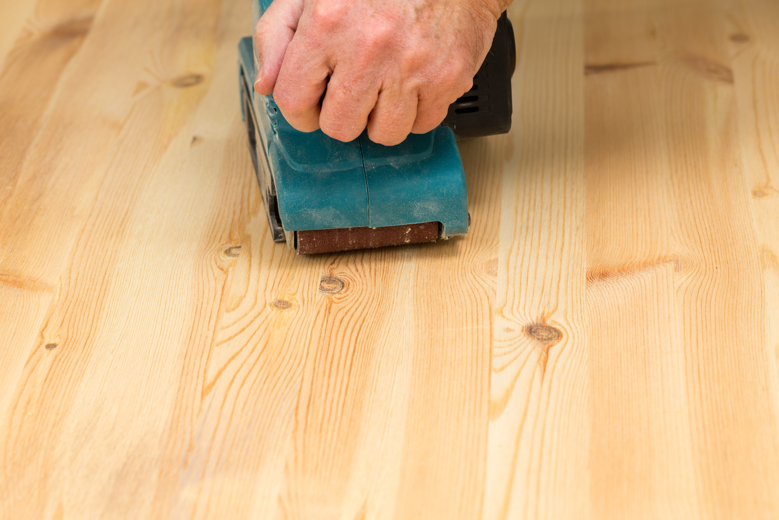 Hand-held sander used on wood floor.