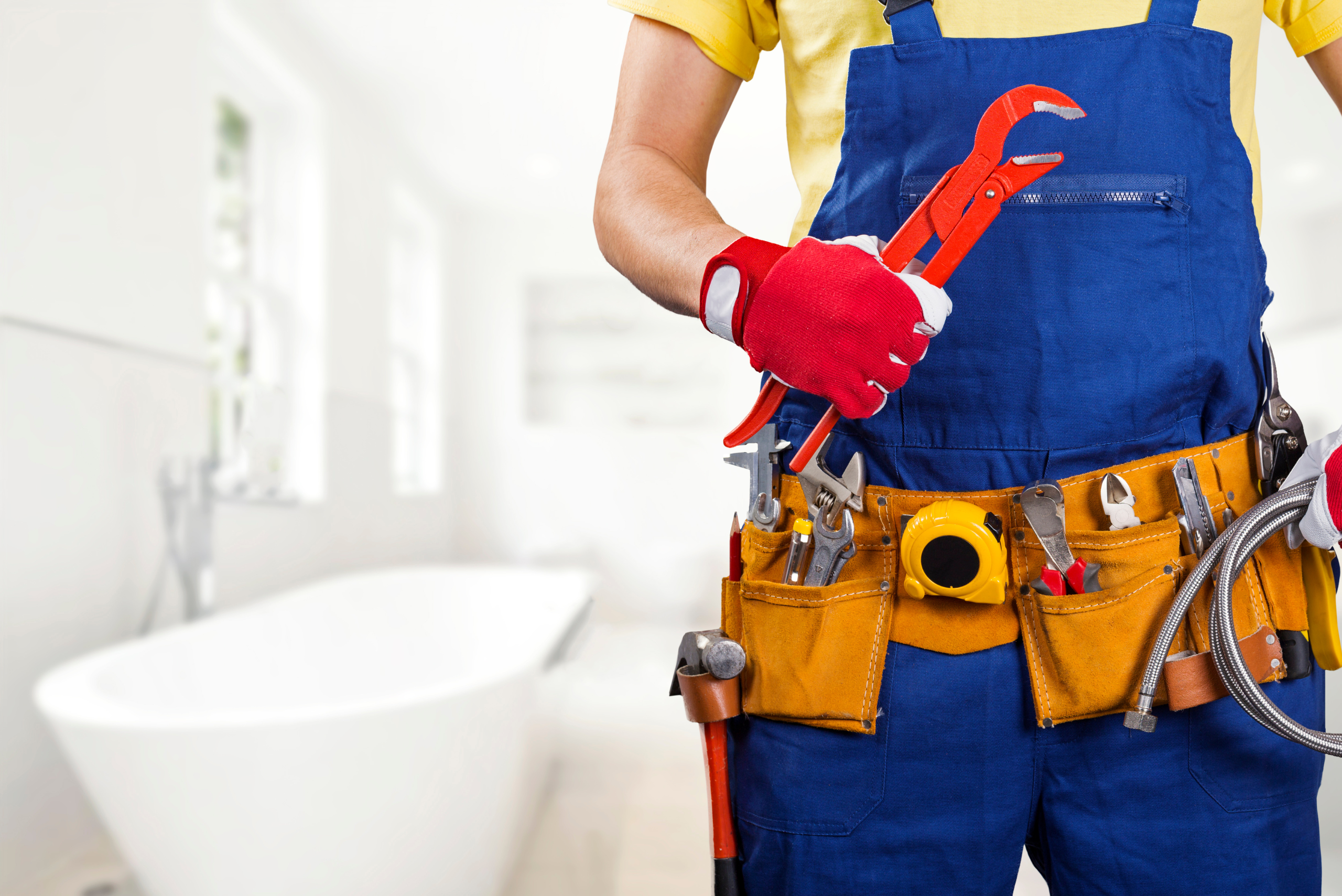 Plumber holding adjustment wrench near a bathtub.