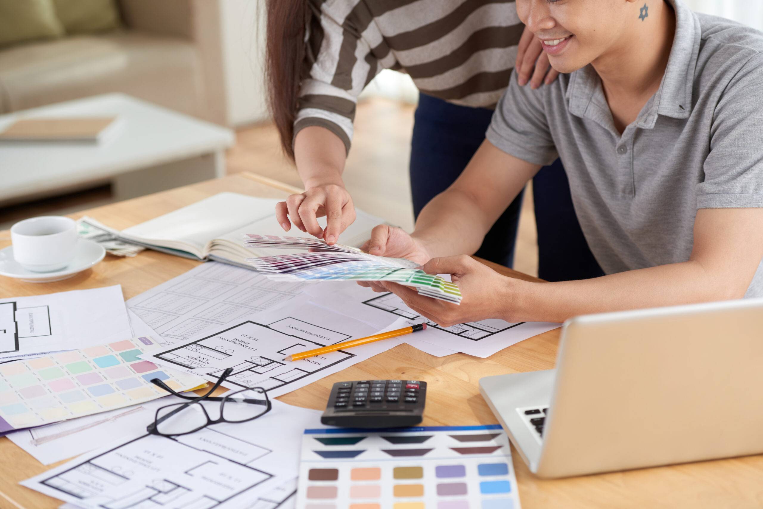 Close-up shot of unrecognizable couple gathered together at home and choosing colors for painting walls in their new apartment with help of color palettes.