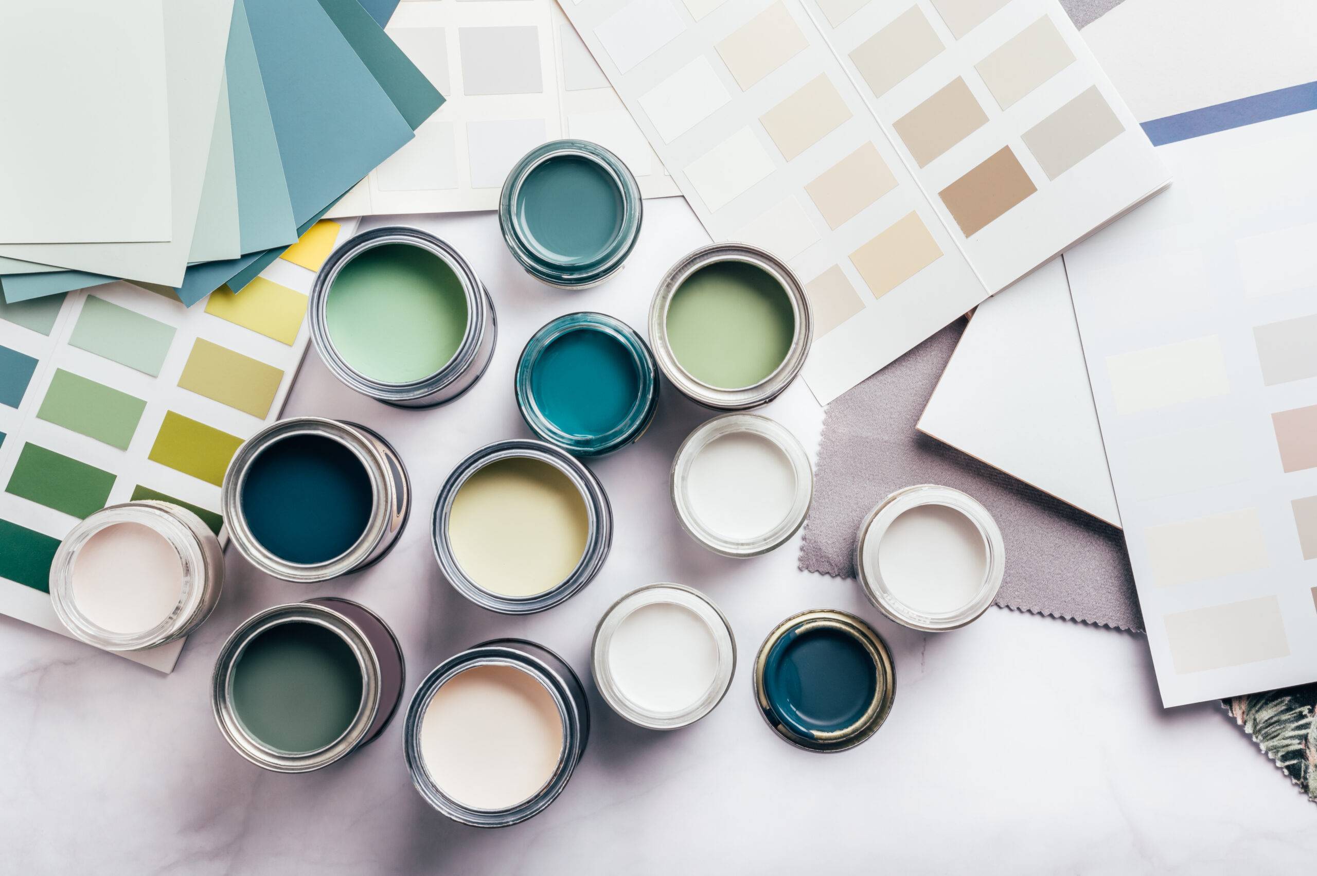 Tiny sample paint cans, different green and beige colors, color charts on the background.