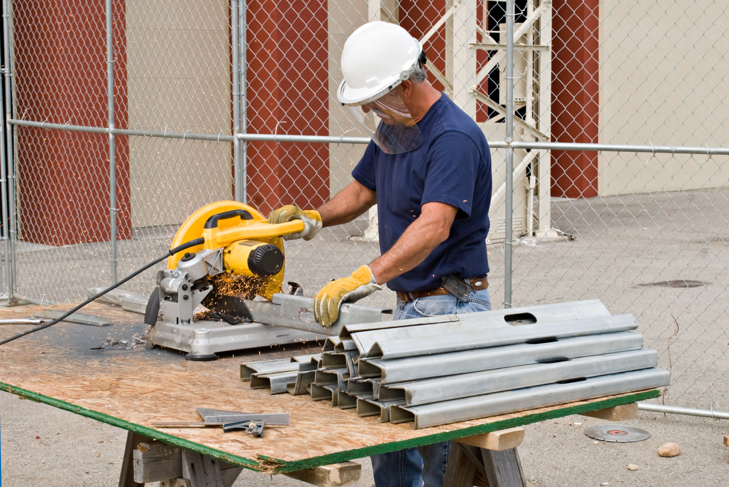 Worker using chop saw to cut metal studs.