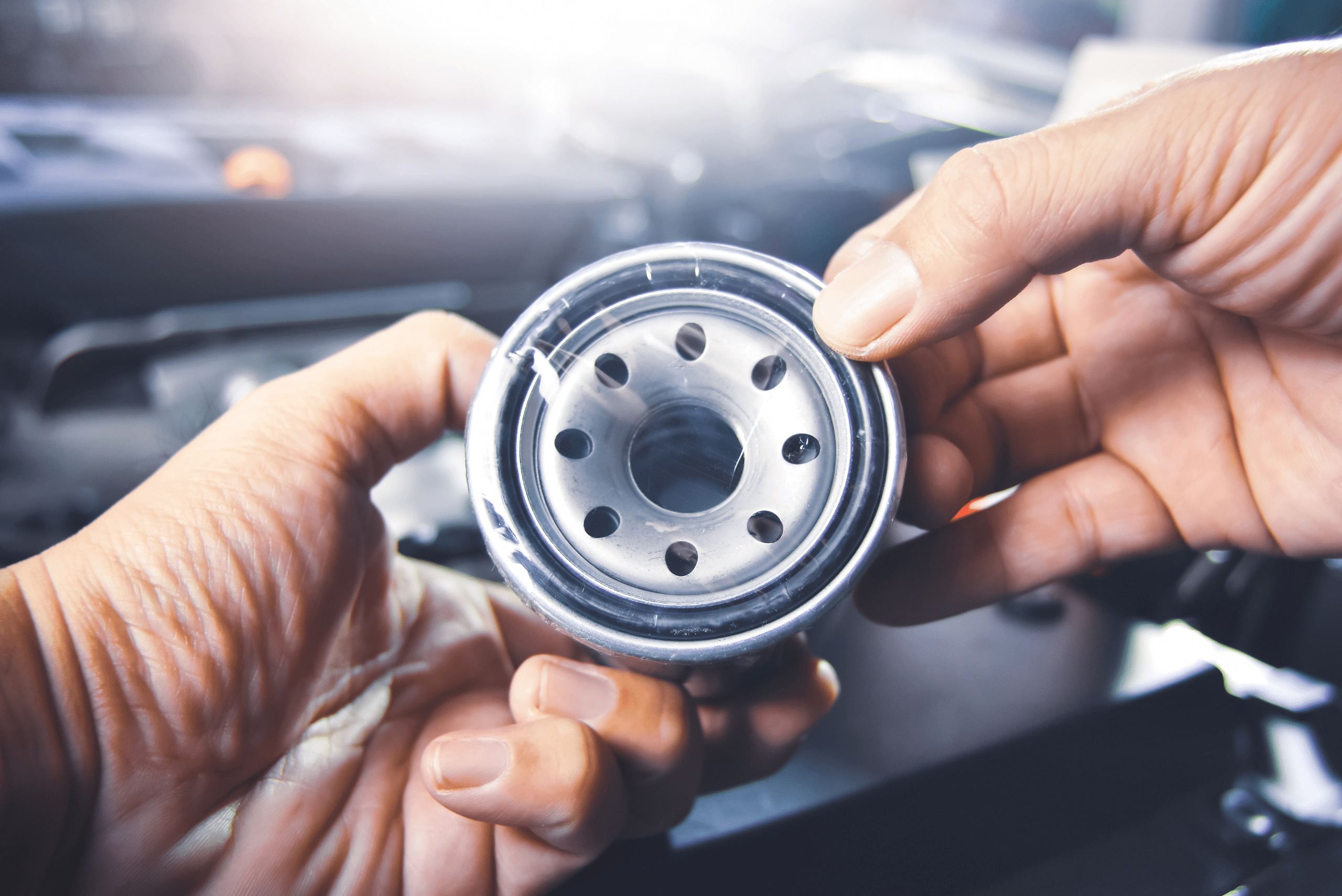 Person removing plastic wrapping from a new engine oil filter