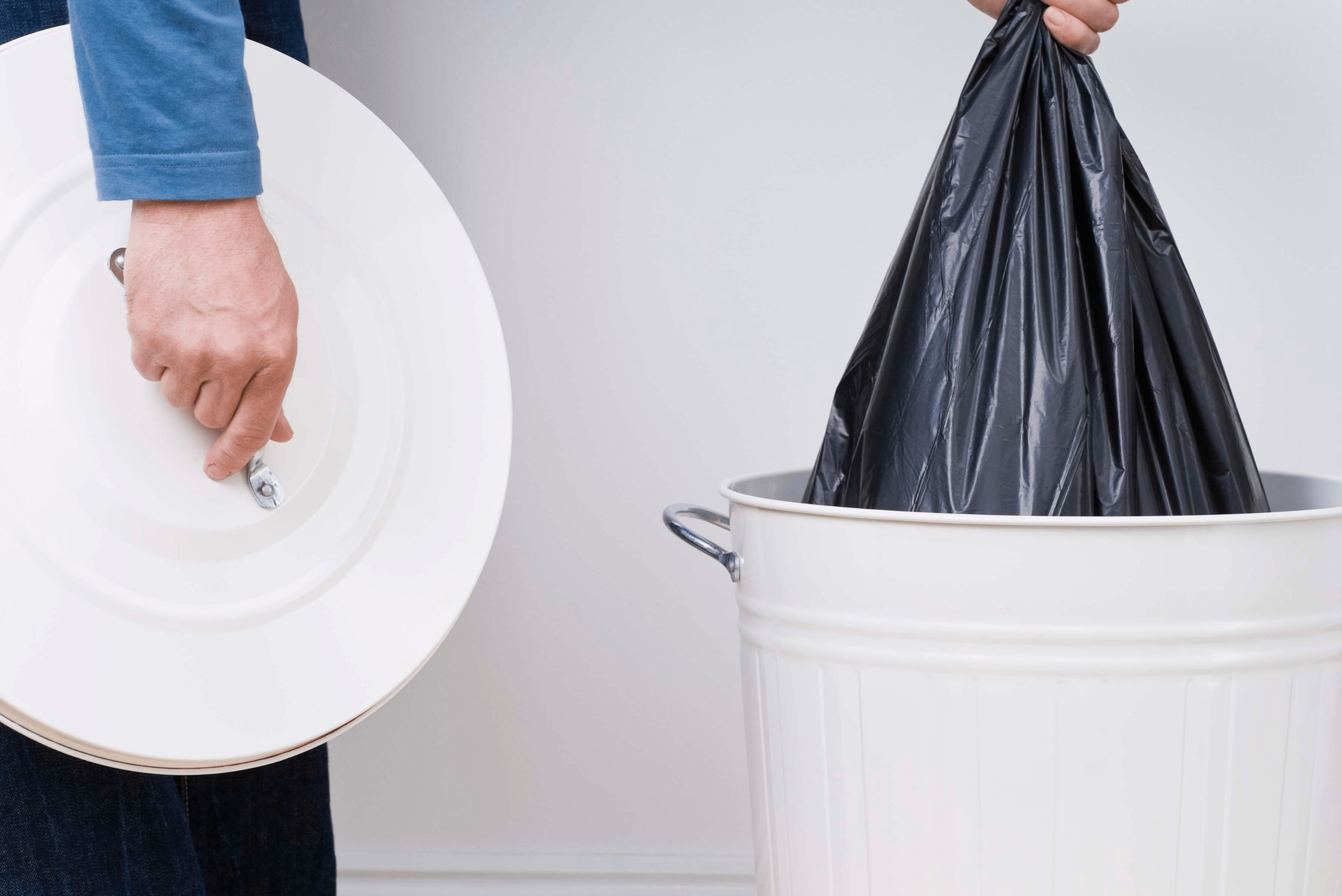 Person emptying trash can by pulling out garbage bag.