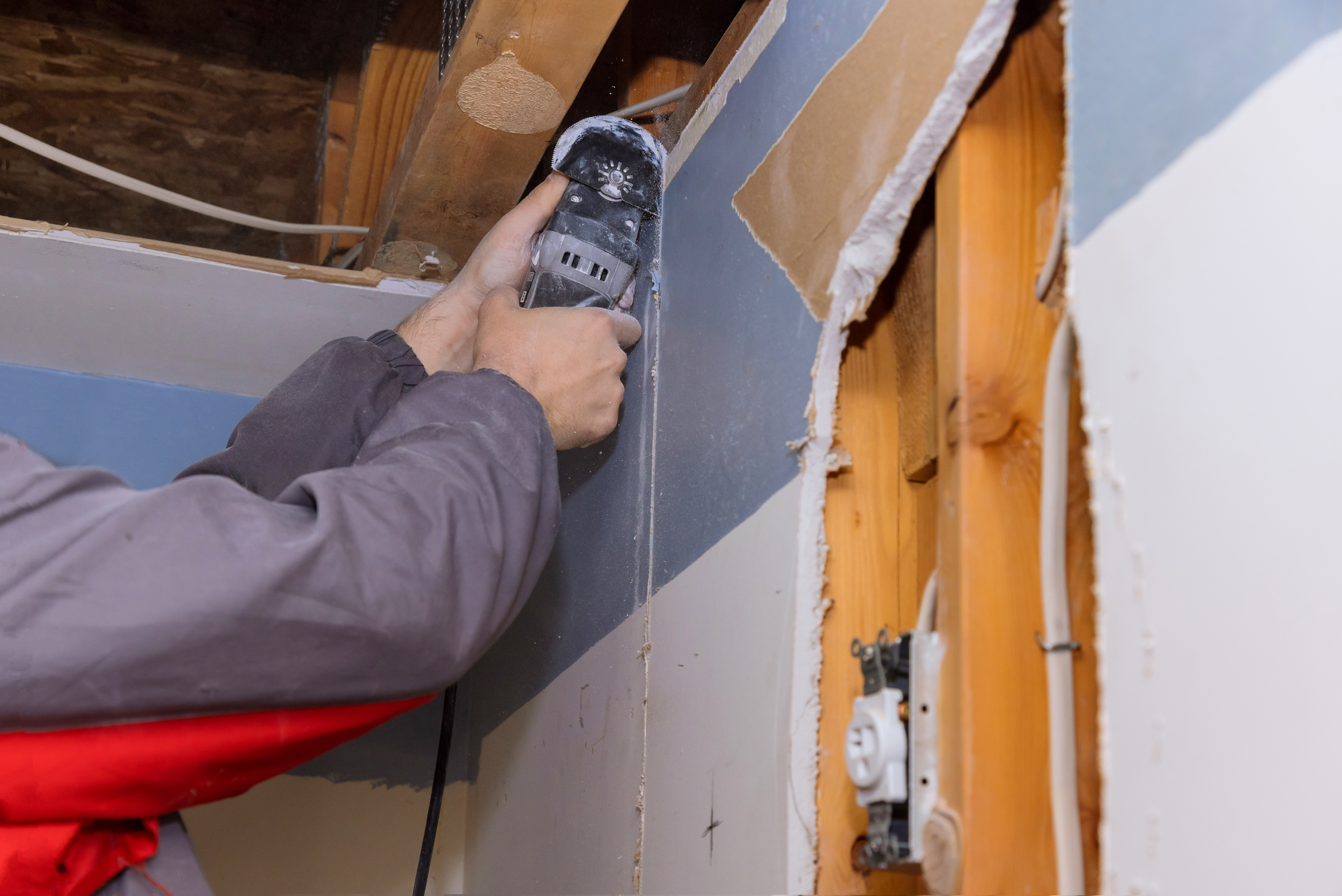 Closeup of someone's handing holding an angle grinder to cut drywall.