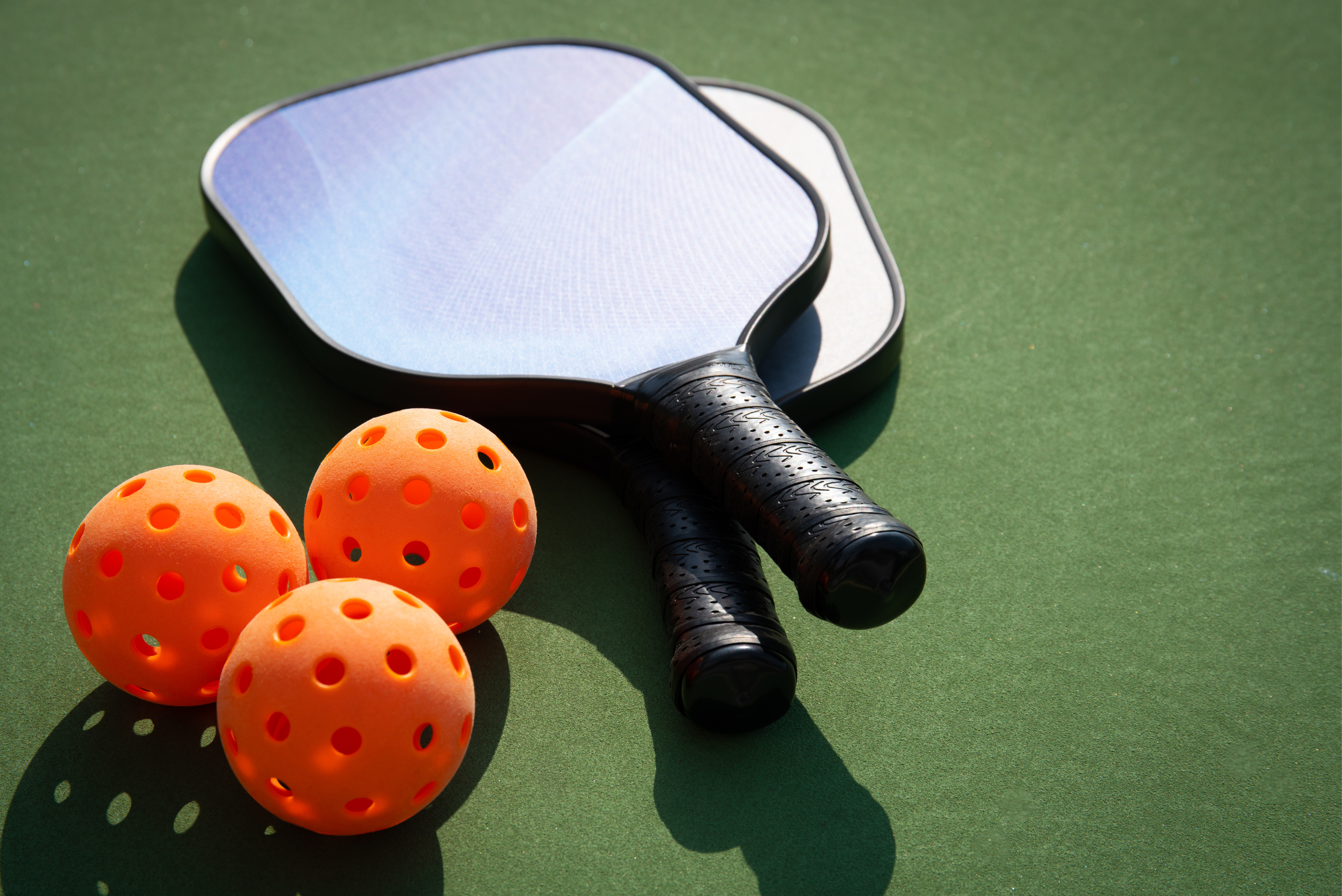 Three orange pickleballs and two rackets.