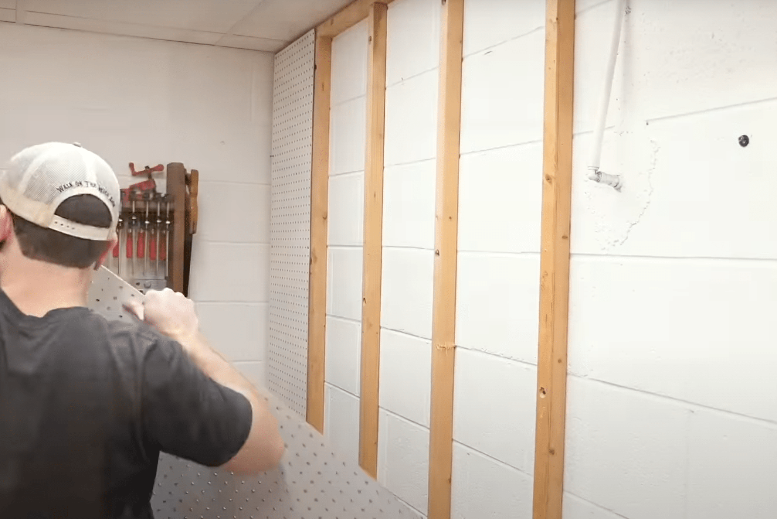 Person preparing the wall for installing a French cleat wall.