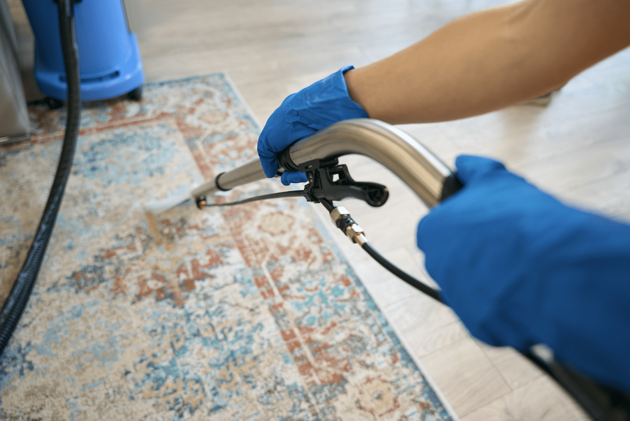 A closeup of someone's arms using a carpet steamer.