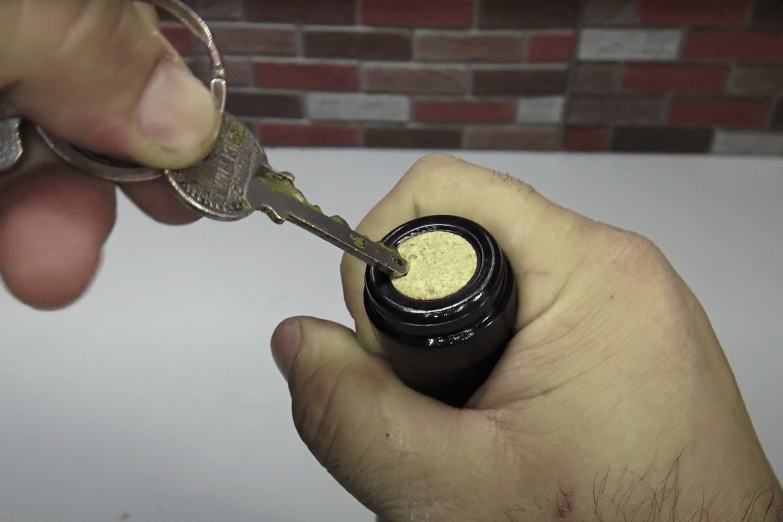 Person using key to open wine bottle.