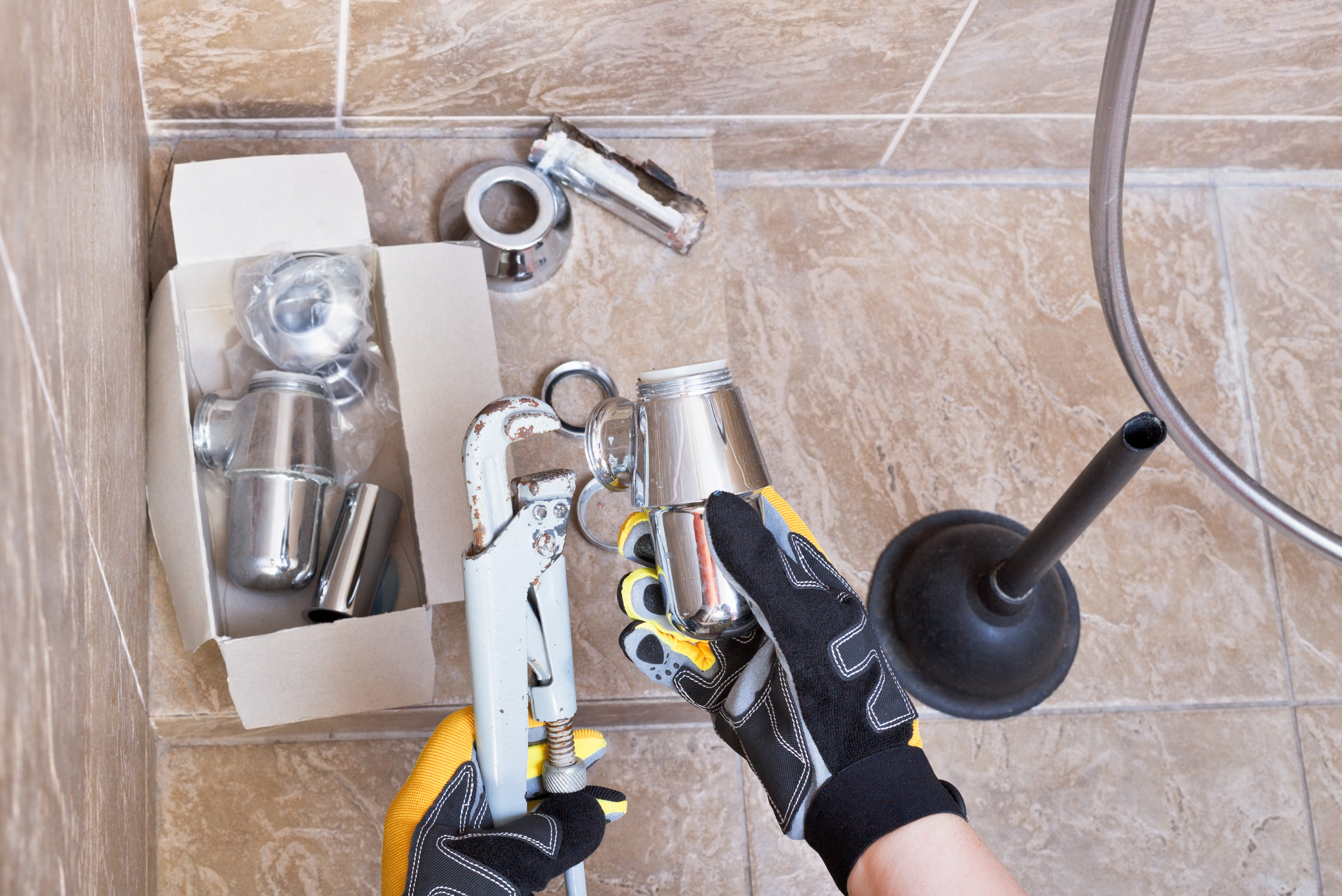 Closeup of someone's hands wearing gloves going through a box of replacement sink parts.