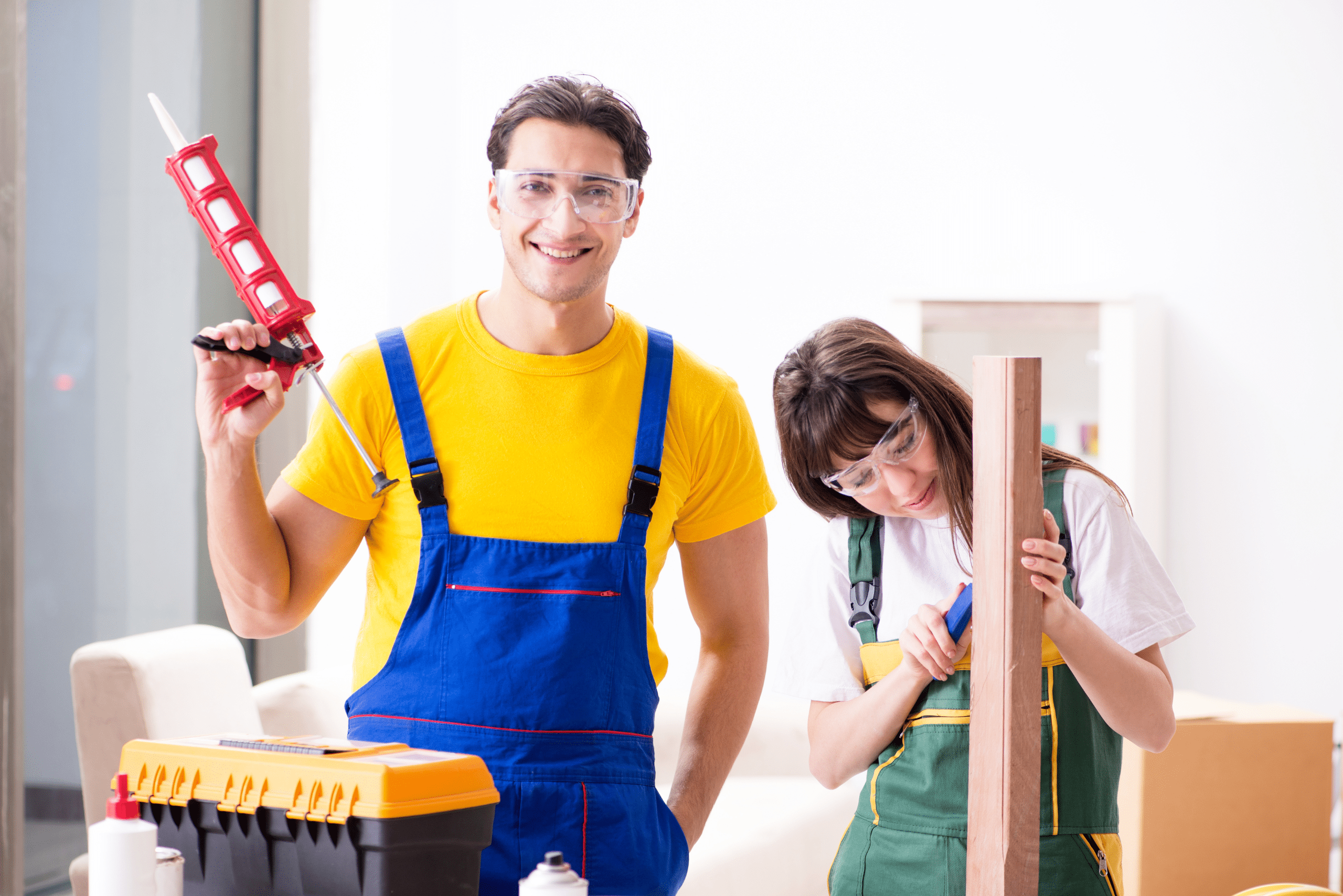 Two people, one holding a caulking gun and another holding a piece of wood.